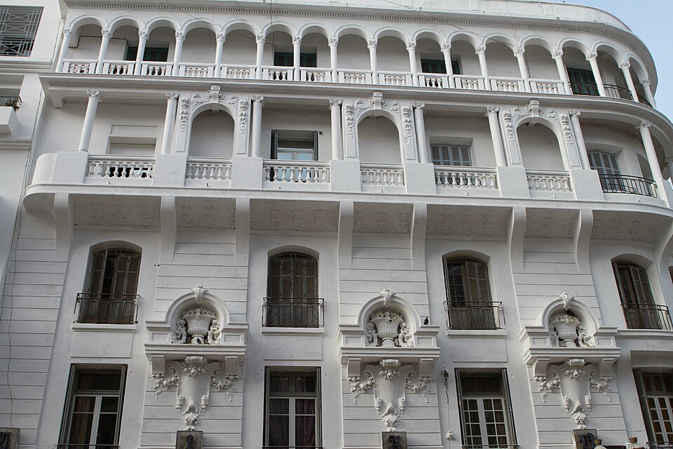 Historic white façade with curved balconies, arched openings and carved ornament in Casablanca